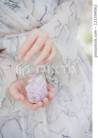 Woman's hand holding a bottle of cherry blossom petals Woman's hand holding a bottle of cherry blossom petals 121594062