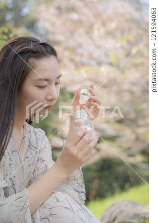 A woman looking at a bottle of cherry blossoms A woman looking at a bottle of cherry blossoms 121594063