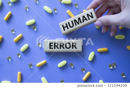 Human Error symbol. Concept word Human Error on wooden blocks. Beautiful purple background with pills. Doctor Hand. Medicine and Human Error concept. Copy space Human Error symbol. Concept word Human Error on wooden blocks. Beautiful purple background with pills. Doctor Hand. Medicine and Human Error concept. Copy space 121594209