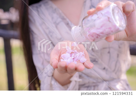 A woman holds a bottle filled with cherry blossom petals 121594331