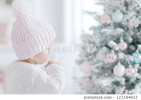 Adorable baby wearing a pink winter outfit in a cozy, festive setting. Snowy winter season, weather and snow theme. 121594652
