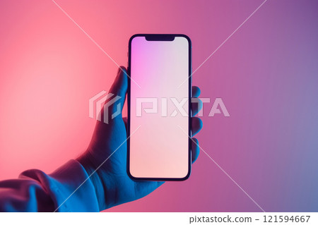 A hand holds a smartphone with a blank screen, set against a richly hued pink and blue gradient background. The image conveys modern technology and lifestyle with a contemporary and stylish aesthetic. 121594667