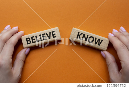 Believe or Know symbol. Concept word Believe or Know on wooden blocks. Businessman hand. Beautiful orange background. Business and Believe or Know concept. Copy space 121594732