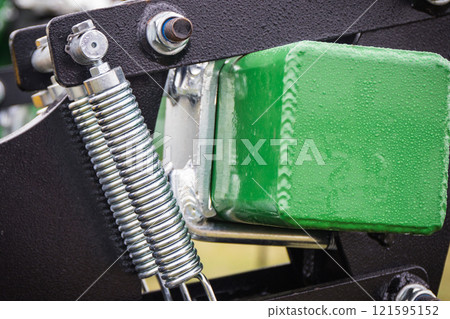 Silver spring made of steel. Part of big industrial or agricultural machine 121595152