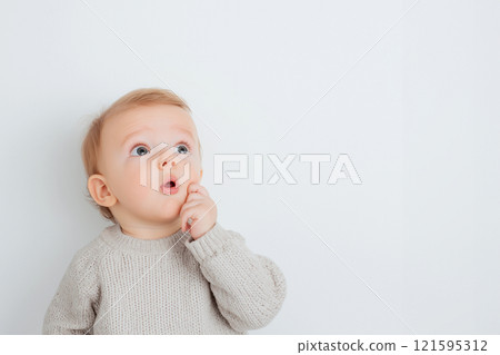 A shocked cute baby with wide eyes and an open mouth looking at the camera, surprise, wow concept. Amazed, excited child, funny reaction on amazing news, loud sound or something new 121595312