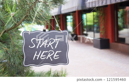 Start Here symbol. Concept word Start Here on black chalk background. Beautiful background with shop and tree. Business and Start Here concept. Copy space 121595460