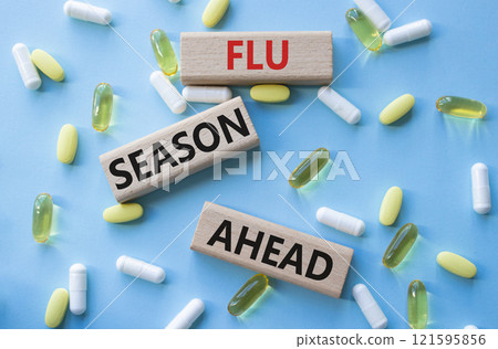 Flu Season Ahead symbol. Concept word Flu Season Ahead on wooden blocks. Beautiful blue background with pills. Medicine and Flu Season Ahead concept. Copy space 121595856