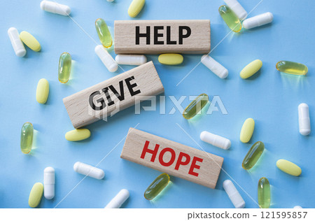 Help Give Hope symbol. Concept word Help Give Hope on wooden blocks. Beautiful blue background with pills. Medicine and Help Give Hope concept. Copy space 121595857