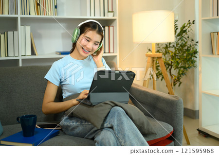 Pretty young woman with headphones enjoying content on digital tablet Pretty young woman with headphones enjoying content on digital tablet 121595968