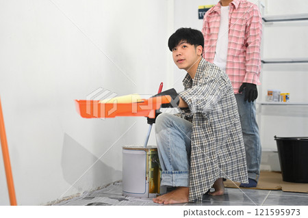 Two painters working on a painting project in an indoor space. Two painters working on a painting project in an indoor space. 121595973
