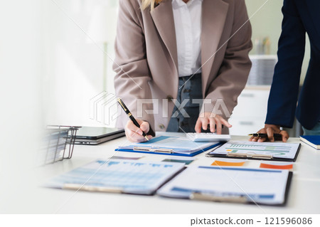 Diverse professionals collaborate on project analysis with financial graphs. Strategic teamwork and insights drive company growth and success. Diverse professionals collaborate on project analysis with financial graphs. Strategic teamwork and insights drive company growth and success. 121596086