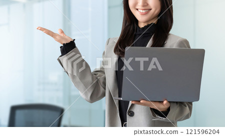 一位微笑的女商人拿著電腦並提供指導 121596204