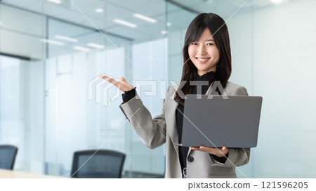 一位微笑的女商人拿著電腦並提供指導 121596205