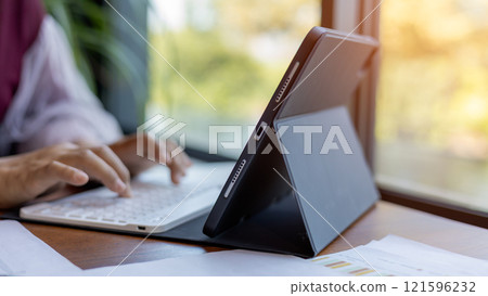 Female hands typing on tablet keyboard on wood desk at office, Technology, Business concept, Business woman analyze the graph of the company performance to create profits and growth. Female hands typing on tablet keyboard on wood desk at office, Technology, Business concept, Business woman analyze the graph of the company performance to create profits and growth. 121596232