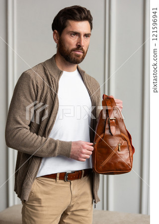 A Stylish and Professional Man Standing with a yellow brown hip pack in a Contemporary Modern Setting. 121596941