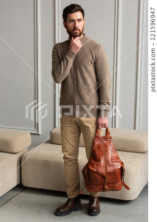 A Stylish and Professional Man Standing with brown yellow backpack in a Contemporary Modern Setting A Stylish and Professional Man Standing with brown yellow backpack in a Contemporary Modern Setting 121596947
