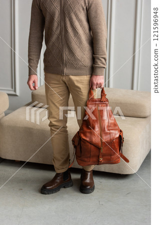 A Stylish and Professional Man Standing with brown yellow backpack in a Contemporary Modern Setting A Stylish and Professional Man Standing with brown yellow backpack in a Contemporary Modern Setting 121596948
