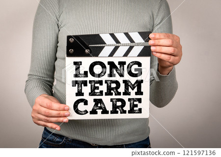 LONG TERM CARE. Hand holding movie clapper LONG TERM CARE. Hand holding movie clapper 121597136