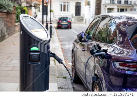 Charging an electric car on the street, greener energy vehicle Charging an electric car on the street, greener energy vehicle 121597171