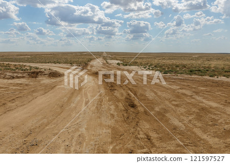 Rugged dirt roads intersecting in the vast steppe landscape of Kazakhstan under a cloudy sky Rugged dirt roads intersecting in the vast steppe landscape of Kazakhstan under a cloudy sky 121597527