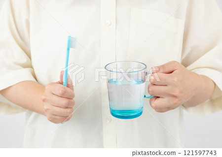 Woman's hand holding a toothbrush and a cup 01 Woman's hand holding a toothbrush and a cup 01 121597743