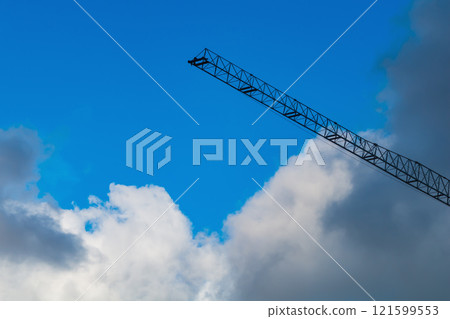 Construction crane on background of rainy clouds. Light rain is coming, predicted by weather forecast. Weather changes make adjustments to construction plans and slow down the speed of work, deadline 121599553