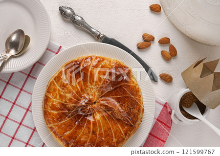 French king's cake or galette des rois with a golden crown placed and presented on a white plate and red napkin background, top view 121599767