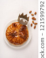 French king's cake or galette des rois with a golden crown placed on it and presented on a white plate and background, top view, copy space 121599792