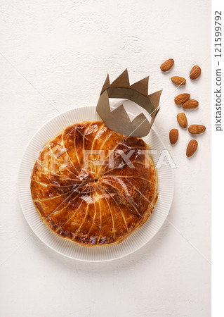 French king's cake or galette des rois with a golden crown placed on it and presented on a white plate and background, top view, copy space French king's cake or galette des rois with a golden crown placed on it and presented on a white plate and background, top view, copy space 121599792