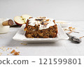 Spicy apple, nuts and oats loaf cake decorated with cream on a white plate 121599801