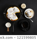 Cinnamon rolls with pumpkin in black pan on the black background, fall baking concept, to view 121599805
