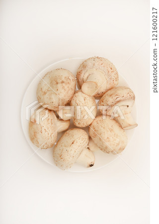 Fresh champignons on a white plate. Mushrooms on a white background. Fresh champignons on a white plate. Mushrooms on a white background. 121600217