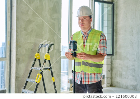 Portrait of male industrial worker in vest helmet with professional equipment 121600308