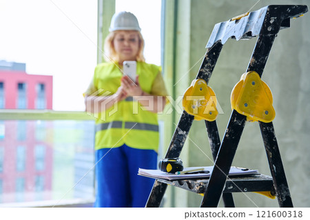 Close-up of construction tools, female industrial worker in the background. 121600318