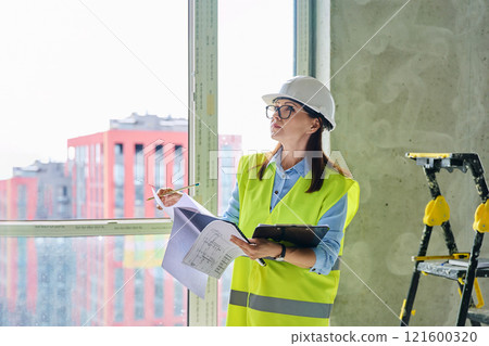 Technical profession woman in protective vest helmet working on construction Technical profession woman in protective vest helmet working on construction 121600320