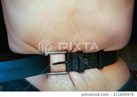 Man tightening waist belt with bare torso, concept of saving money, fasting, strike, hunger strike 121600978