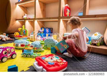Toddler exploring educational toys in a lively playroom. Concept of early childhood development and creativity Toddler exploring educational toys in a lively playroom. Concept of early childhood development and creativity 121600983