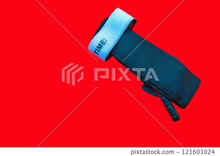 Medical tourniquet to stop bleeding. A device for slowing blood flow to the extremities, self-rescue, should be in everyone's first aid kit on red background Medical tourniquet to stop bleeding. A device for slowing blood flow to the extremities, self-rescue, should be in everyone's first aid kit on red background 121601024