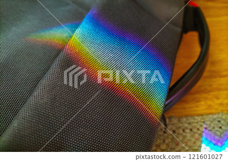 Rainbow reflection from mirror on black textured bag on the floor. Interference of sunlight, school physics course and optical phenomena in Nature Rainbow reflection from mirror on black textured bag on the floor. Interference of sunlight, school physics course and optical phenomena in Nature 121601027
