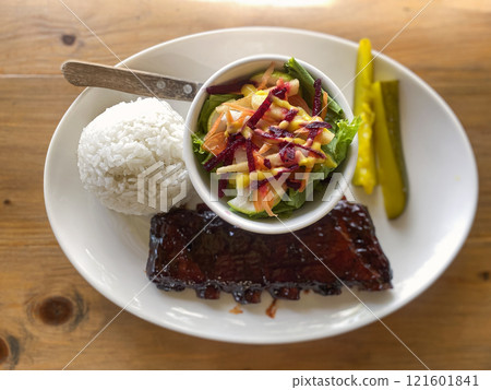 caramelized fried BBQ beef ribs with vegetable salad, rice and pickled cucumbers 121601841