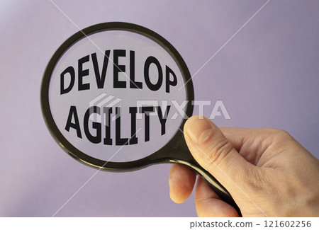 Develop agility symbol. Concept word Develop agility on magnifying glass. Beautiful pink background. Businessman hand. Business and Develop agility concept. Copy space 121602256