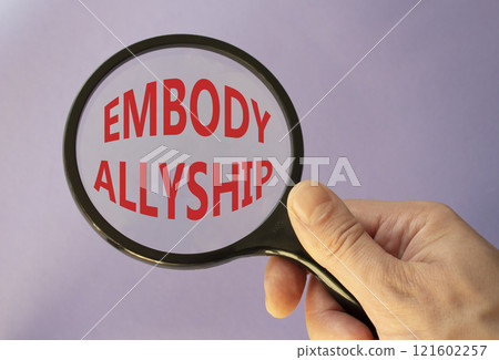 Embody Allyship symbol. Concept word Embody Allyship on magnifying glass. Beautiful purple background. Businessman hand. Business and Embody Allyship concept. Copy space 121602257