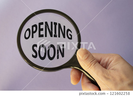 Opening soon symbol. Magnifying Glass with Concept word Opening soon. Beautiful purple background. Businessman hand. Business and Opening soon concept. Copy space 121602258