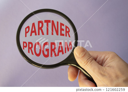 Partner Program symbol. Concept words Partner Program on magnifying glass. Businessman hand. Beautiful purple background. Business and Partner Program concept. Copy space. 121602259