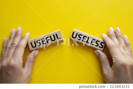 Useful or Useless symbol. Concept word Useful or Useless on wooden blocks. Businessman hand. Beautiful yellow background. Business and Useful or Useless concept. Copy space 121603231