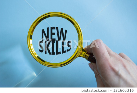 New skills symbol. Magnifying Glass with Concept word New skills. Businessman hand. Beautiful blue background. Business and New skills concept. Copy space New skills symbol. Magnifying Glass with Concept word New skills. Businessman hand. Beautiful blue background. Business and New skills concept. Copy space 121603316