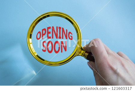 Opening soon symbol. Magnifying Glass with Concept word Opening soon. Businessman hand. Beautiful blue background. Business and Opening soon concept. Copy space Opening soon symbol. Magnifying Glass with Concept word Opening soon. Businessman hand. Beautiful blue background. Business and Opening soon concept. Copy space 121603317