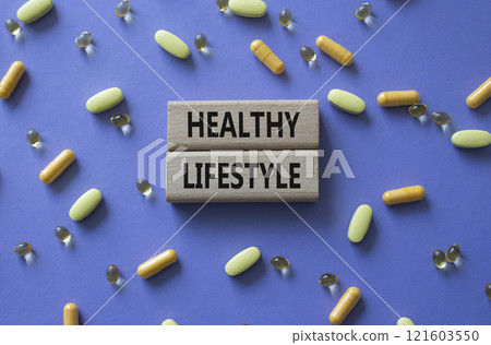 Healthy Lifestyle symbol. Concept words Healthy Lifestyle on wooden blocks. Beautiful purple background with pills. Medicine and Healthy Lifestyle concept. Copy space. 121603550