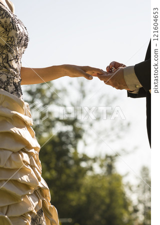 Closeup of groom placing a wedding ring on his brides finger 121604653