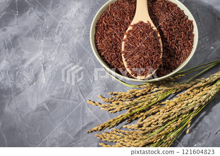 awesome red-rice in a bowl with spoon and ears of rice on wood awesome red-rice in a bowl with spoon and ears of rice on wood 121604823